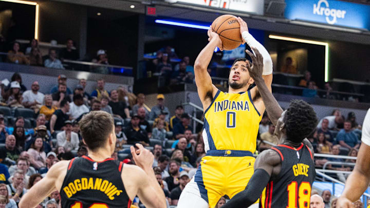Apr 14, 2024; Indianapolis, Indiana, USA; Indiana Pacers guard Tyrese Haliburton (0) shoots the ball while Atlanta Hawks guard Bogdan Bogdanovic (13) and forward Mouhamed Gueye (18) defend in the first half at Gainbridge Fieldhouse. Mandatory Credit: Trevor Ruszkowski-Imagn Images