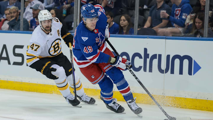 Sep 23, 2025; New York, New York, USA; New York Rangers right wing Jaroslav Chmelar (49) carries the puck in front of Boston Bruins center Mark Kastelic (47) during the first period of a preseason game at Madison Square Garden. Mandatory Credit: Vincent Carchietta-Imagn Images