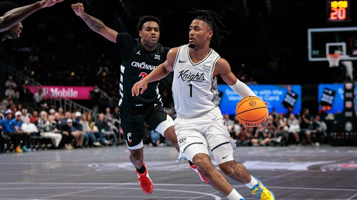 Mar 11, 2026; Kansas City, MO, USA; UCF Knights guard Themus Fulks (1) drives to the basket around Cincinnati Bearcats guard Jizzle James (2) during the first half at T-Mobile Center. Mandatory Credit: William Purnell-Imagn Images