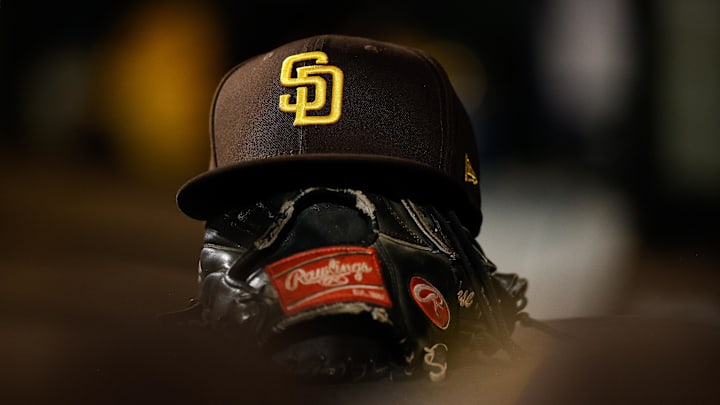 Jun 17, 2022; Denver, Colorado, USA; A detail view of a San Diego Padres hat on a glove in the dugout in the ninth inning against the Colorado Rockies at Coors Field. Mandatory Credit: Isaiah J. Downing-Imagn Images