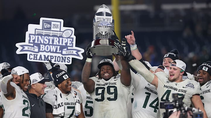 Dec 27, 2019; Bronx, New York, USA; Michigan State defensive tackle Raequan Williams (99) and defensive end Kenny Willekes (48) celebrate with the trophy after defeating the Wake Forest Demon Deacons in the Pinstripe Bowl at Yankee Stadium. Mandatory Credit: Brad Penner-Imagn Images