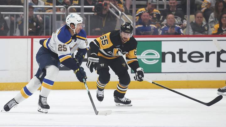 Mar 13, 2025; Pittsburgh, Pennsylvania, USA; St. Louis Blues center Jordan Kyrou (25) moves the puck against Pittsburgh Penguins defenseman Erik Karlsson (65) during the first period at PPG Paints Arena. Mandatory Credit: Charles LeClaire-Imagn Images
