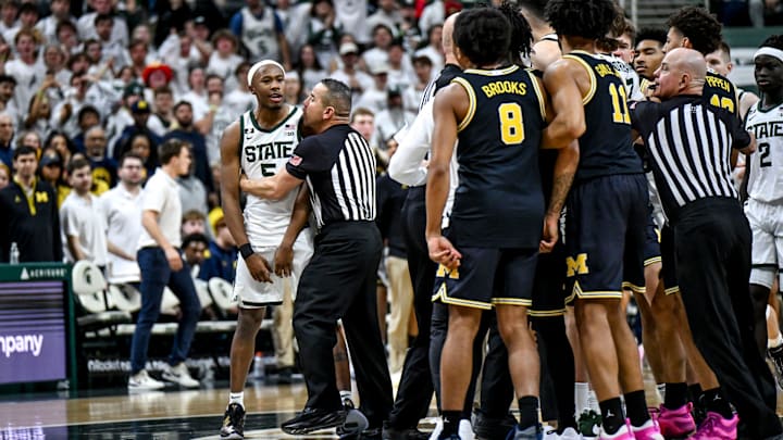Michigan State's Tre Holloman, left, is held back by a referee after pushing Michigan's L.J. Cason and Phat Phat Brooks back off the Spartans logo as senior teammates prepare to kiss the floor during the second half on Sunday, March 9, 2025, at the Breslin Center in East Lansing.
