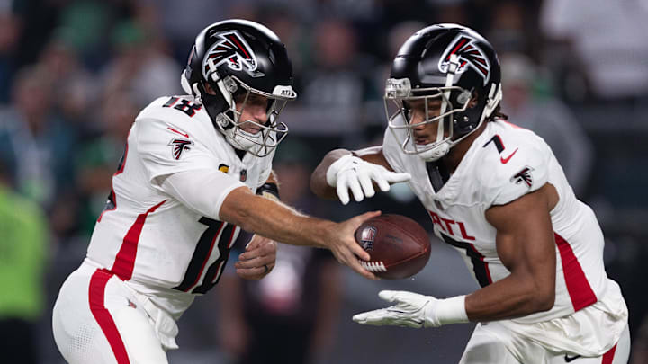 Atlanta Falcons quarterback Kirk Cousins (18) hands off to running back Bijan Robinson.