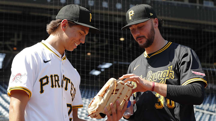 Jul 22, 2025; Pittsburgh, Pennsylvania, USA;  Seth Hernandez (left) the Pittsburgh Pirates first round and number six overall pick in the 2025 first year player draft looks at the glove of Pirates pitcher Paul Skenes (30) before the game against the Detroit Tigers at PNC Park. Mandatory Credit: Charles LeClaire-Imagn Images