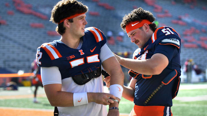 Sep 14, 2024; Champaign, Illinois, USA; Illinois fighting Illini long snapper Aiden Hall helps long snapper Pat Farrell with his jersey before a game against the Central Michigan Chippewas at Memorial Stadium. Mandatory Credit: Ron Johnson-Imagn Images