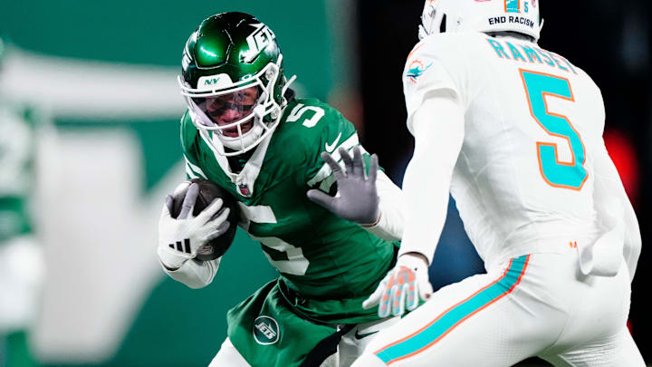 New York Jets wide receiver Garrett Wilson (5) runs with the ball as he tries to find a way past Miami Dolphins cornerback Jalen Ramsey (5), Sunday January 5, 2025, in East Rutherford.