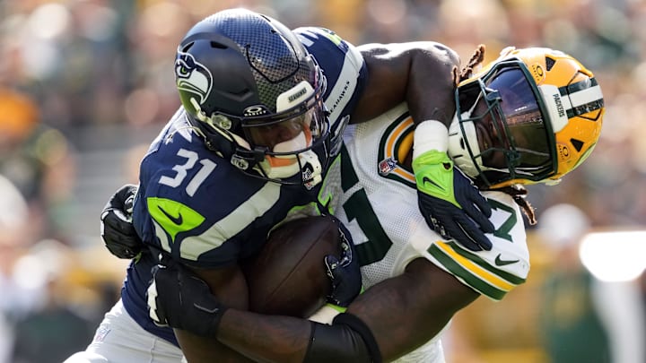 Aug 23, 2025; Green Bay, Wisconsin, USA;  Green Bay Packers defensive lineman Brenton Cox Jr. (57) tackles Seattle Seahawks running back Jacardia Wright (31) during the second quarter at Lambeau Field.