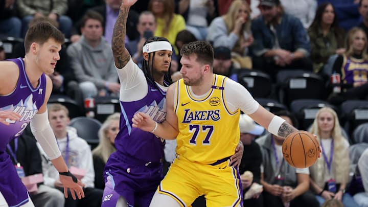 Feb 12, 2025; Salt Lake City, Utah, USA;  Los Angeles Lakers guard Luka Doncic (77) dribbles against Utah Jazz guard Jordan Clarkson (00) during the second half at Delta Center. Mandatory Credit: Chris Nicoll-Imagn Images