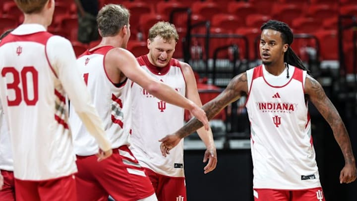 Indiana basketball guard Lamar Wilkerson high-fives teammate Trent Sisley, standing between Tucker DeVries and Ian Stephens.