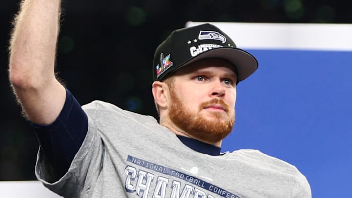 Jan 25, 2026; Seattle, WA, USA; Seattle Seahawks quarterback Sam Darnold (14) celebrates with the trophy on the podium after defeating the Los Angeles Rams in the 2026 NFC Championship Game at Lumen Field. Mandatory Credit: Kevin Ng-Imagn Images