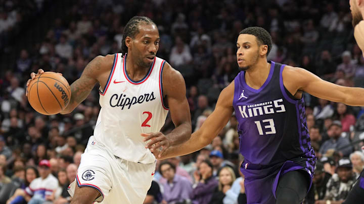 Apr 11, 2025; Sacramento, California, USA; Los Angeles Clippers forward Kawhi Leonard (2) dribbles against Sacramento Kings forward Keegan Murray (13) and forward Domantas Sabonis (right) during the fourth quarter at Golden 1 Center.