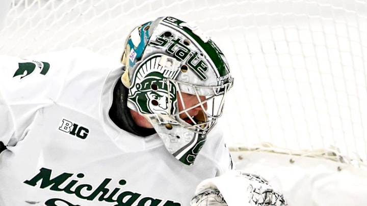 Michigan State's Trey Augustine, center, stops the puck after a Michigan shot during the first period on Friday, Dec. 5, 2025, at Munn Ice Arena in East Lansing.