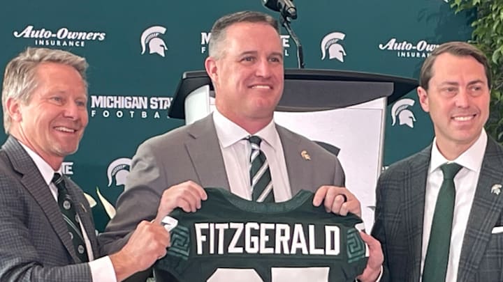 Michigan State Spartans head coach Pat Fitzgerald, center, poses with a namesake jersey next to MSU president Kevin Guskiewicz, left, and athletic director J Batt, right, during Fitzgerald's introductory press conference on Tuesday, Dec. 2, 2025. Michigan State Spartans head coach Pat Fitzgerald, center, poses with a namesake jersey next to MSU president Kevin Guskiewicz, left, and athletic director J Batt, right, during Fitzgerald's introductory press conference on Tuesday, Dec. 2, 2025.