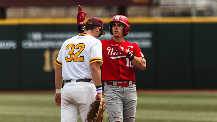Nebraska right fielder Drew Grego celebrates as Minnesota first baseman Jack Bello walks back to the bag.