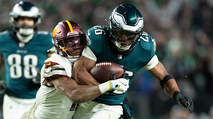 Nov 14, 2024; Philadelphia, Pennsylvania, USA; Philadelphia Eagles running back Saquon Barkley (26) runs with the ball against Washington Commanders safety Jeremy Chinn (11) and cornerback Noah Igbinoghene (1) during the third quarter at Lincoln Financial Field. Mandatory Credit: Bill Streicher-Imagn Images