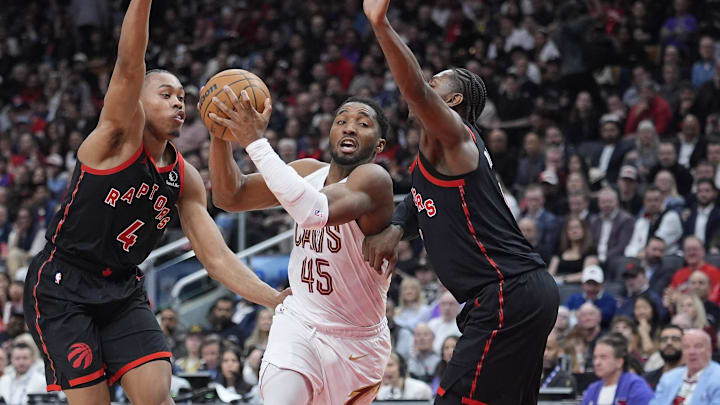 Apr 23, 2026; Toronto, Ontario, CAN; Cleveland Cavaliers guard Donovan Mitchell (45) drives to the basket against Toronto Raptors guard Scottie Barnes (4) and forward RJ Barrett (9) during the second half of game three of the first round of the 2026 NBA Playoffs at Scotiabank Arena. Mandatory Credit: John E. Sokolowski-Imagn Images