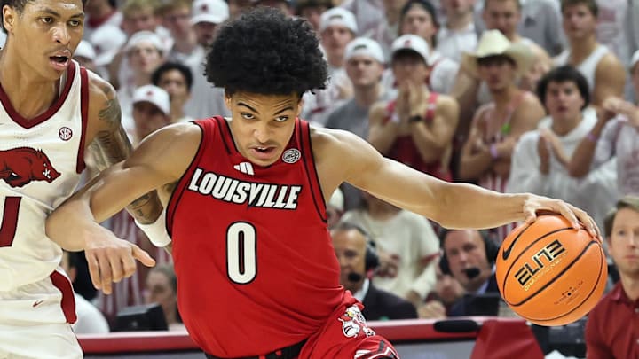 Dec 3, 2025; Fayetteville, Arkansas, USA; Louisville Cardinals guard Mikel Brown Jr (0) dribbles around Arkansas Razorbacks guard Meleek Thomas (1) during the second half at Bud Walton Arena. Arkansas won 89-80. Mandatory Credit: Nelson Chenault-Imagn Images