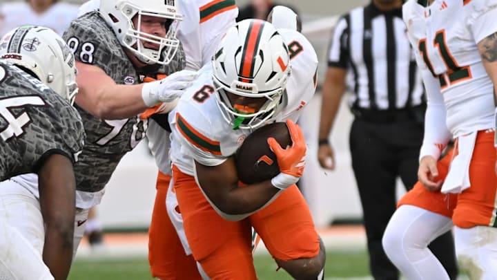 Nov 22, 2025; Blacksburg, Virginia, USA;  Miami (FL) Hurricanes running back Charmar Brown (6) runs the ball as Virginia Tech Hokies linebacker Jaden Keller (24) defends at Lane Stadium. Mandatory Credit: Brian Bishop-Imagn Images