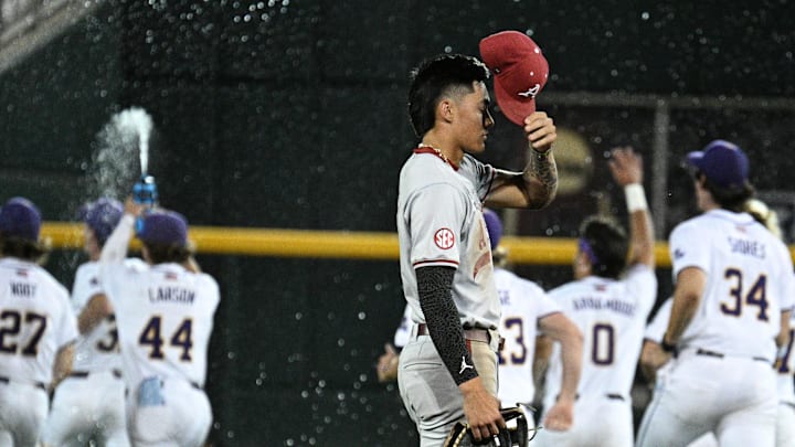 Jun 18, 2025; Omaha, Neb, USA;  Arkansas Razorbacks shortstop Wehiwa Aloy (9) reacts as LSU Tigers players celebrate the win at Charles Schwab Field. Mandatory Credit: Steven Branscombe-Imagn Images