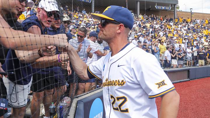 Jun 5, 2026; Morgantown, WV, USA; West Virginia Mountaineers head coach Steve Sabins celebrates with Pat McAfee in the stands after defeating the Cal Poly Mustangs at Kendrick Family Ballpark. Mandatory Credit: Ben Queen-Imagn Images