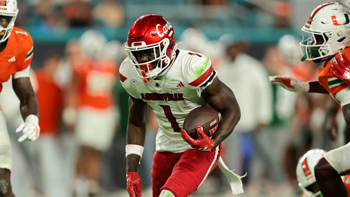 Oct 17, 2025; Miami Gardens, Florida, USA; Louisville Cardinals running back Isaac Brown (1) carries the football against Miami Hurricanes linebacker Mohamed Toure (1) and linebacker Wesley Bissainthe (31) during the first quarter at Hard Rock Stadium. Mandatory Credit: Sam Navarro-Imagn Images Oct 17, 2025; Miami Gardens, Florida, USA; Louisville Cardinals running back Isaac Brown (1) carries the football against Miami Hurricanes linebacker Mohamed Toure (1) and linebacker Wesley Bissainthe (31) during the first quarter at Hard Rock Stadium. Mandatory Credit: Sam Navarro-Imagn Images
