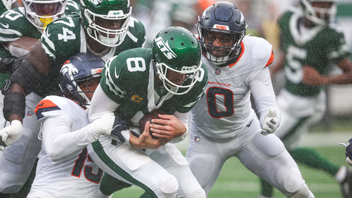 Sep 29, 2024; East Rutherford, New Jersey, USA; New York Jets quarterback Aaron Rodgers (8) is tackled by Denver Broncos linebacker Nik Bonitto (15) and linebacker Jonathon Cooper (0) during the first half at MetLife Stadium. 