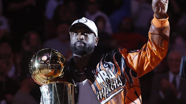 Feb 3, 2026; Miami, Florida, USA;  Former Miami Heat guard Dwayne Wade holds the Larry O' Brien trophy during a ceremony to honor 20 years since they won their first NBA Championship during halftime  at Kaseya Center. Mandatory Credit: Rhona Wise-Imagn Images
