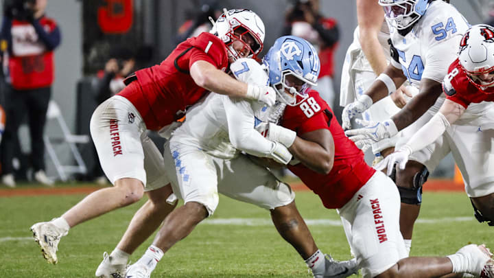 Nov 29, 2025; Raleigh, North Carolina, USA;  NC State Wolfpack linebacker Caden Fordham (1) and defensive end Isaiah Shirley (88) tackles North Carolina Tar Heels quarterback Gio Lopez (7) during the first half of the game against North Carolina Tar Heels at Carter-Finley Stadium.  Mandatory Credit: Jaylynn Nash-Imagn Images