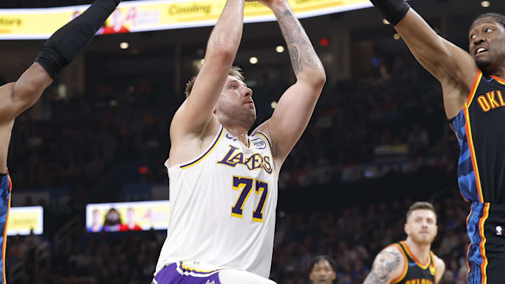 Apr 6, 2025; Oklahoma City, Oklahoma, USA; Los Angeles Lakers guard Luka Doncic (77) drives to the basket between Oklahoma City Thunder guard Shai Gilgeous-Alexander (2) and forward Jalen Williams (8) during the second quarter at Paycom Center. Mandatory Credit: Alonzo Adams-Imagn Images