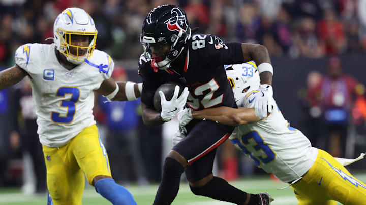 Jan 11, 2025; Houston, Texas, USA; Houston Texans wide receiver Diontae Johnson (82) runs the ball after a reception against Los Angeles Chargers defensive back Deane Leonard (33) and safety Derwin Jarnes Jr. (3) during the third quarter in an AFC wild card game at NRG Stadium. Mandatory Credit: Troy Taormina-Imagn Images