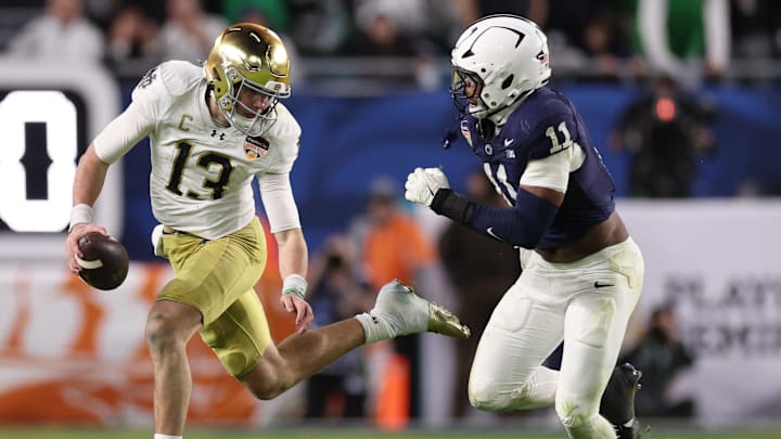 Notre Dame Fighting Irish quarterback Riley Leonard (13) runs the ball pressured by Penn State Nittany Lions defensive end Abdul Carter (11)