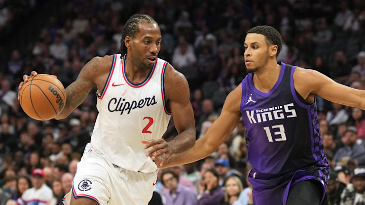 Apr 11, 2025; Sacramento, California, USA; Los Angeles Clippers forward Kawhi Leonard (2) dribbles against Sacramento Kings forward Keegan Murray (13) and forward Domantas Sabonis (right) during the fourth quarter at Golden 1 Center.