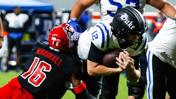 Nov 9, 2024; Raleigh, North Carolina, USA; North Carolina State Wolfpack cornerback Devon Marshall (16) tackles Duke Blue Devils quarterback Grayson Loftis (12) during the second half of the game at Carter-Finley Stadium. Mandatory Credit: Jaylynn Nash-Imagn Images