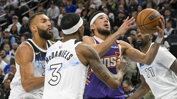 Nov 17, 2024; Minneapolis, Minnesota, USA; Phoenix Suns guard Devin Booker (1) cuts through Minnesota Timberwolves center Rudy Gobert (27), forward Jaden McDaniels (3), and center Naz Reid (11) for a layup during the second quarter at Target Center. Mandatory Credit: Nick Wosika-Imagn Images