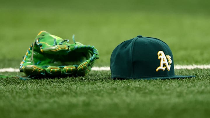 Jul 22, 2025; Arlington, Texas, USA;  Athletics glove and hat on the field before the game against the Texas Rangers at Globe Life Field. Mandatory Credit: Kevin Jairaj-Imagn Images