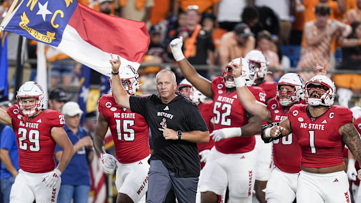 Sep 7, 2024; Charlotte, North Carolina, USA; North Carolina State Wolfpack head coach Dave Doeren leads his team onto the field against the Tennessee Volunteers during the first quarter at the Dukes Mayo Classic at Bank of America Stadium. Mandatory Credit: Jim Dedmon-Imagn Images