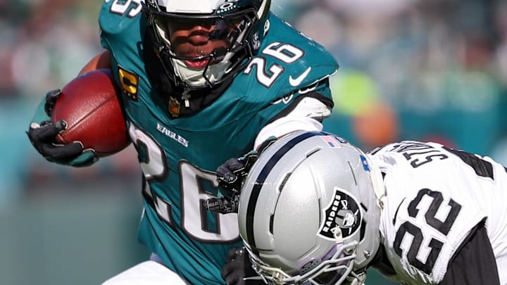 Dec 14, 2025; Philadelphia, Pennsylvania, USA; Philadelphia Eagles running back Saquon Barkley (26) runs the ball against Las Vegas Raiders cornerback Eric Stokes (22) during the first quarter at Lincoln Financial Field. Mandatory Credit: Bill Streicher-Imagn Images