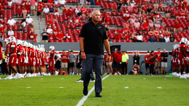 Aug 29, 2024; Raleigh, North Carolina, USA; North Carolina State Wolfpack head coach Dave Doeren between his players before the first half of the game against Western Carolina Catamounts at Carter-Finley Stadium. Mandatory Credit: Jaylynn Nash-Imagn Images