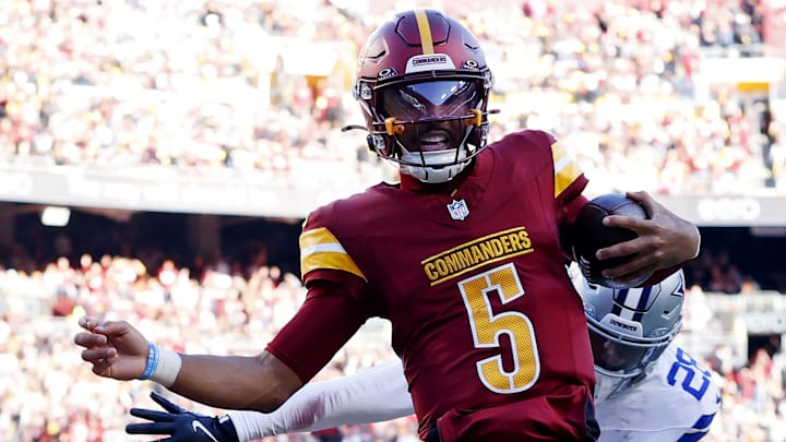 Nov 24, 2024; Landover, Maryland, USA; Washington Commanders quarterback Jayden Daniels (5) runs for a touchdown against Dallas Cowboys safety Malik Hooker (28) during the third quarter at Northwest Stadium. Mandatory Credit: Peter Casey-Imagn Images