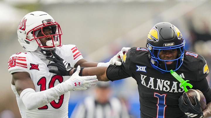 Nov 28, 2025; Lawrence, Kansas, USA; Kansas Jayhawks wide receiver Emmanuel Henderson Jr. (1) runs with the ball against Utah Utes cornerback Blake Cotton (16) during the second half at David Booth Kansas Memorial Stadium. Mandatory Credit: Jay Biggerstaff-Imagn Images