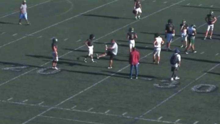 Royal High football coach Adam Brubaker has been put on leave after he kicks a football at a player's groin at practice. Royal High football coach Adam Brubaker has been put on leave after he kicks a football at a player's groin at practice.