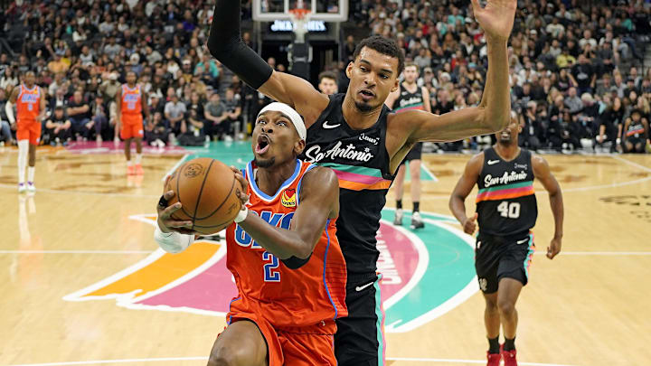 Dec 23, 2025; San Antonio, Texas, USA; Oklahoma City Thunder guard Shai Gilgeous-Alexander (2) drives to the basket past San Antonio Spurs forward Victor Wembanyama (1) during the first half at Frost Bank Center. Mandatory Credit: Scott Wachter-Imagn Images