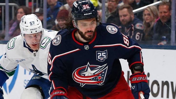 Jan 15, 2026; Columbus, Ohio, USA; Columbus Blue Jackets right wing Kirill Marchenko (86) pickls up a loose puck as \Vancouver Canucks defenseman Tyler Myers (57) defends during the second period at Nationwide Arena. Mandatory Credit: Russell LaBounty-Imagn Images