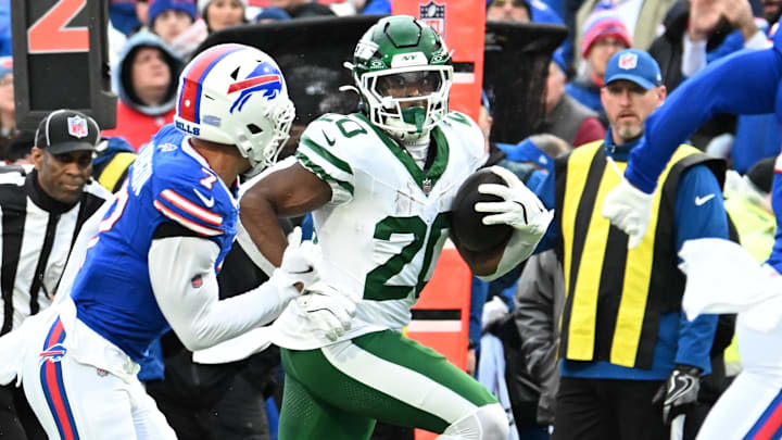 Dec 29, 2024; Orchard Park, New York, USA; New York Jets running back Breece Hall (20) carries the ball as Buffalo Bills cornerback Taron Johnson (7) defends in the first quarter at Highmark Stadium. Mandatory Credit: Mark Konezny-Imagn Images