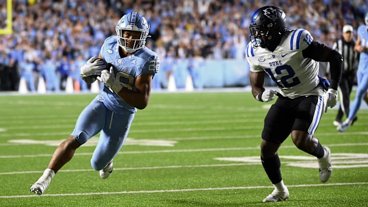 Nov 11, 2023; Chapel Hill, North Carolina, USA; North Carolina Tar Heels running back Omarion Hampton (28) with the ball as Duke Blue Devils linebacker Tre Freeman (12) defends in the first overtime at Kenan Memorial Stadium. Mandatory Credit: Bob Donnan-Imagn Images