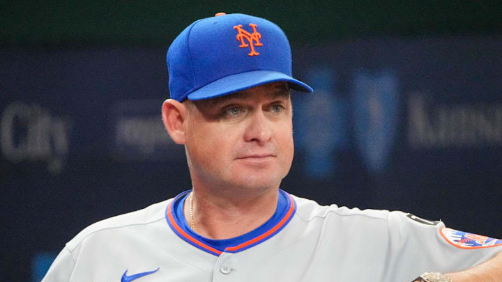 Jul 11, 2025; Kansas City, Missouri, USA; New York Mets manager Carlos Mendoza (64) watches from the dugout against the Kansas City Royals prior to a game at Kauffman Stadium. Mandatory Credit: Denny Medley-Imagn Images