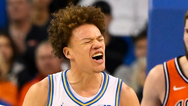 Feb 21, 2026; Los Angeles, California, USA; UCLA guard Trent Perry (0) reacts to scoring against Illinois during the second half while UCLA forward Tyler Bilodeau (34) (left) and Illinois center Tomislav Ivisic (13) (right) look on at Pauley Pavilion presented by Wescom Financial. Mandatory Credit: Robert Hanashiro-Imagn Images