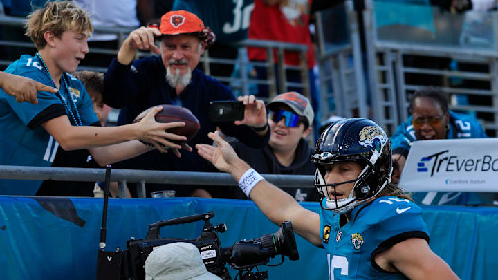 Jacksonville Jaguars quarterback Trevor Lawrence (16) hands the ball to a fan after scoring a rushing touchdown during the first quarter of an NFL football matchup at EverBank Stadium, Sunday, Dec. 14, 2025, in Jacksonville, Fla. [Corey Perrine/Florida Times-Union]