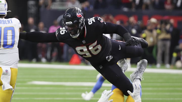 Jan 11, 2025; Houston, Texas, USA;  Los Angeles Chargers quarterback Justin Herbert (10) is defended by Houston Texans defensive end Denico Autry (96) in the second quarter in an AFC wild card game at NRG Stadium. Mandatory Credit: Thomas Shea-Imagn Images